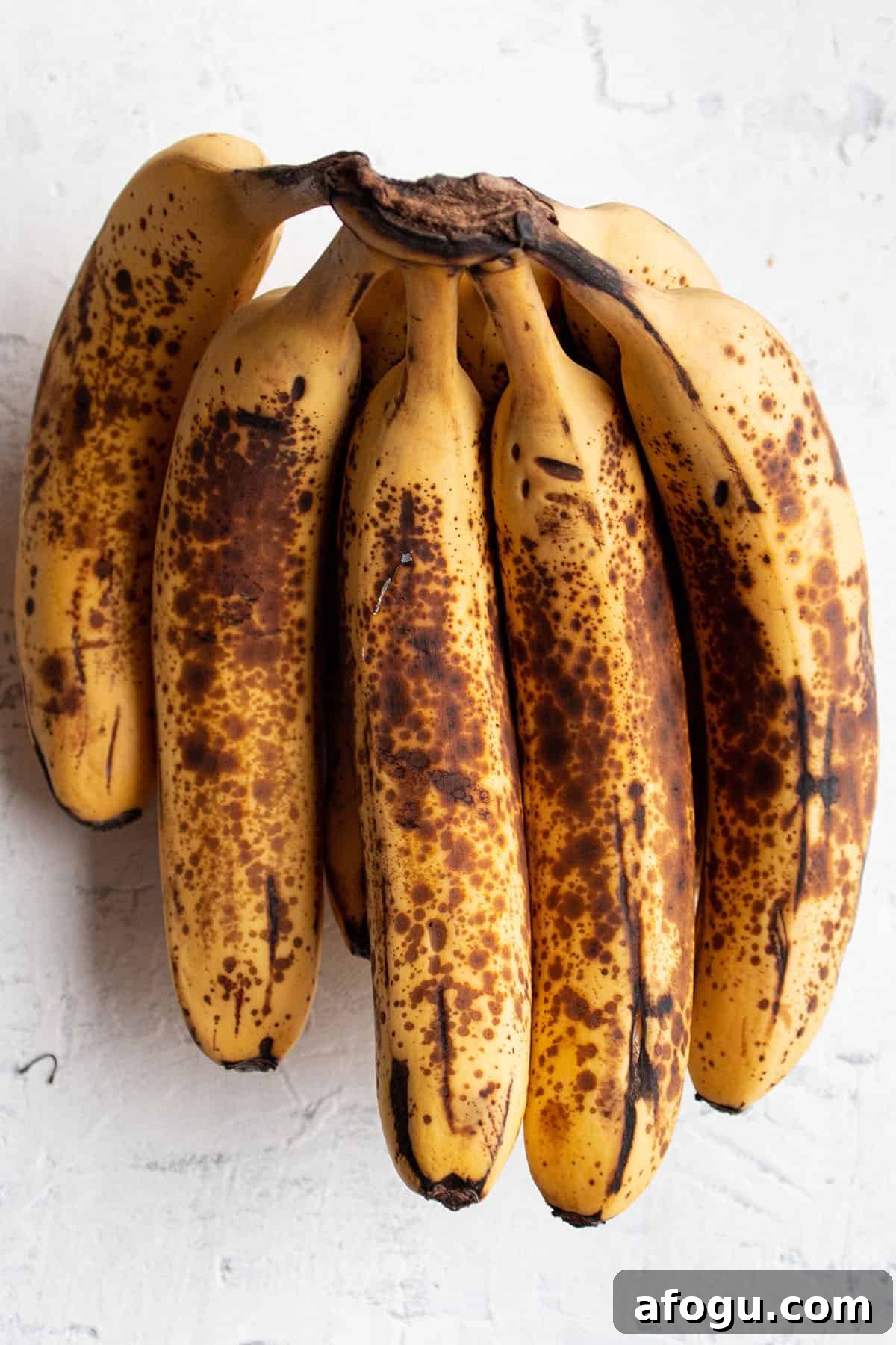 A bundle of overly ripe banana with brown speckles.