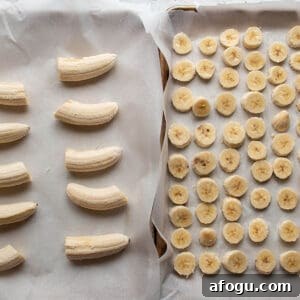 Two sheet pans lined with parchment paper, one with sliced bananas and one with halved bananas.