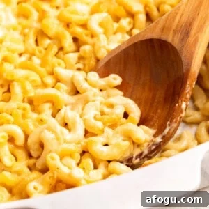 Copycat Cracker Barrel Mac and Cheese Recipe — Creamy Southern Style 10 A wooden spoon scooping Cracker Barrel mac and cheese from a baking dish.
