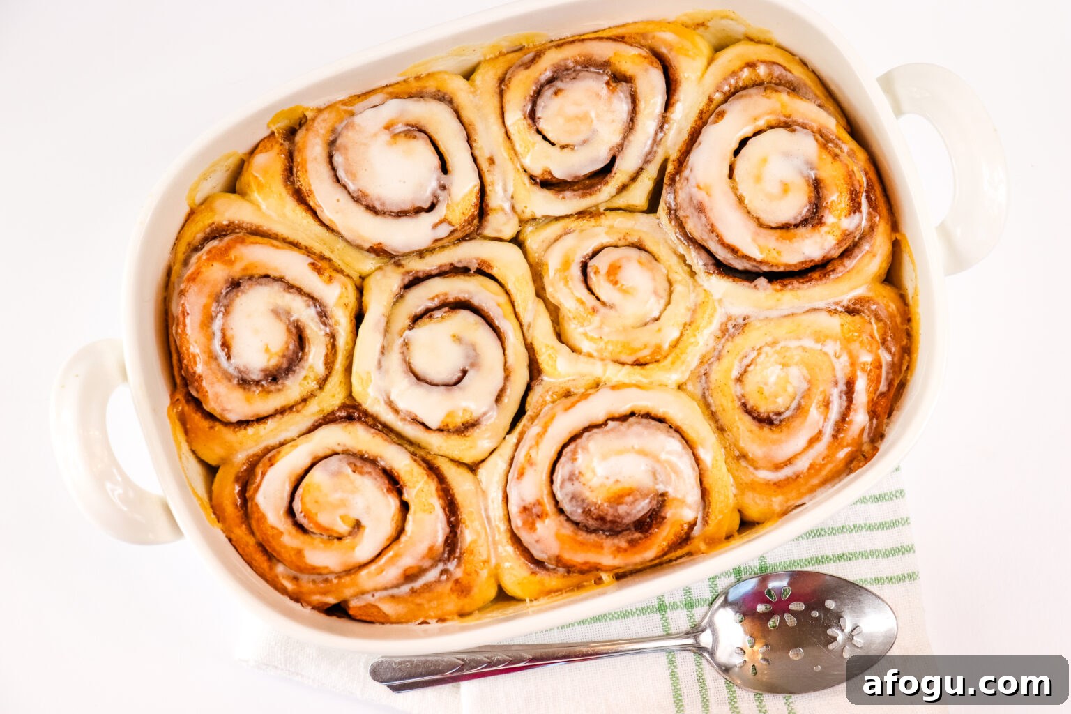 viral tiktok cinnamon rolls in large white baking dish with serving spoon beside it