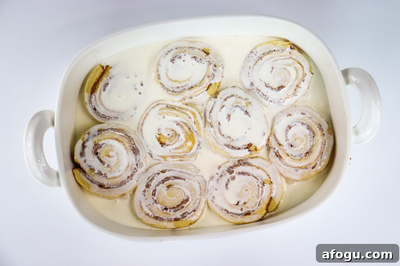 heavy whipping cream poured over cinnamon rolls in baking dish