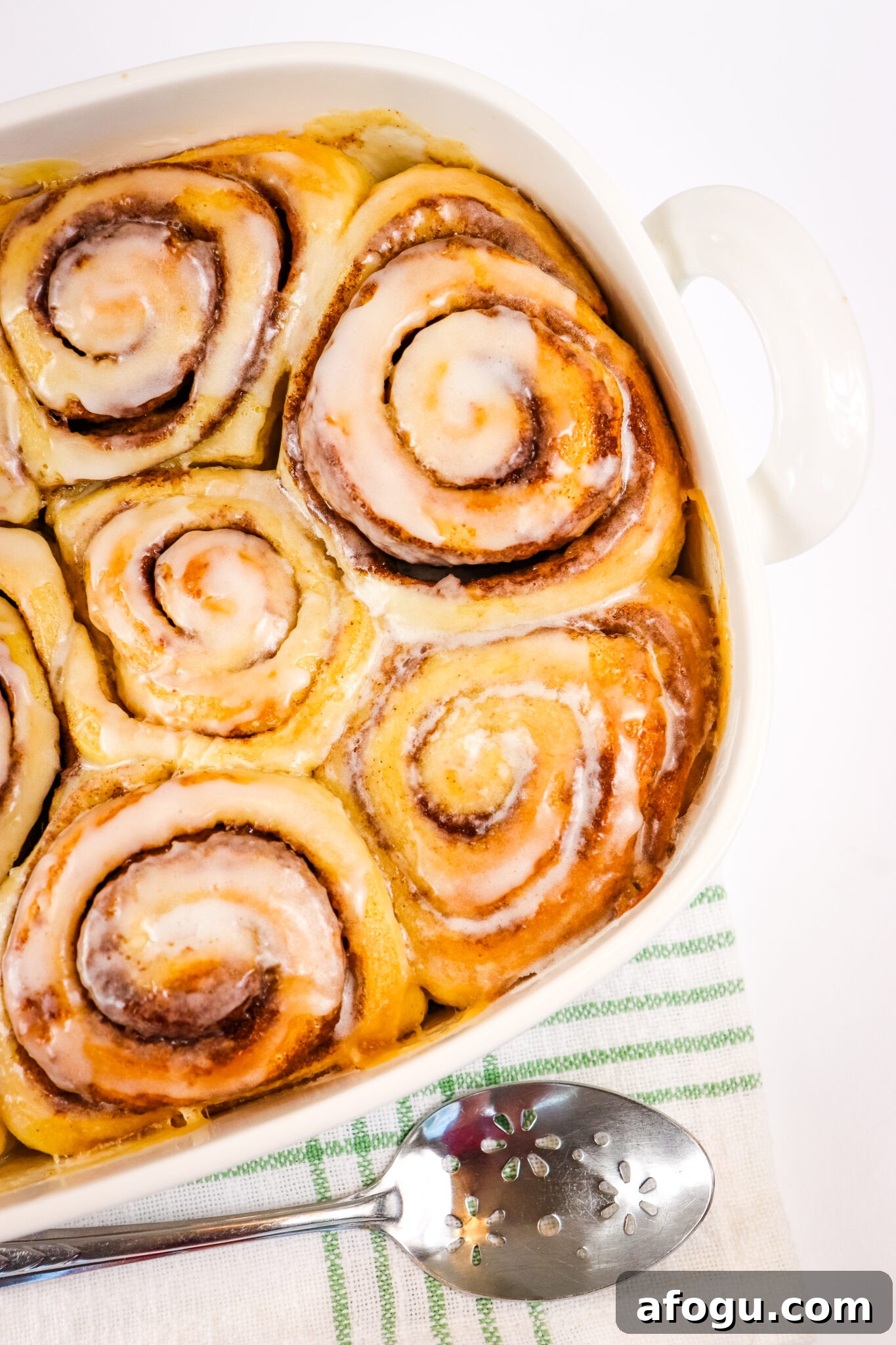 cream cheese frosting poured over baked cinnamon rolls