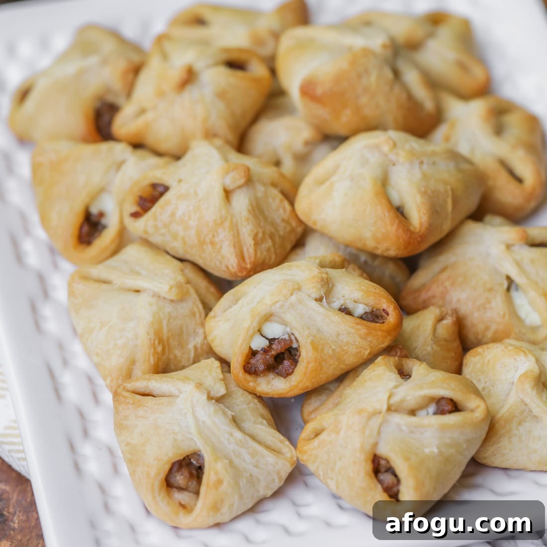 Sausage cream cheese crescent rolls piled onto a white plate