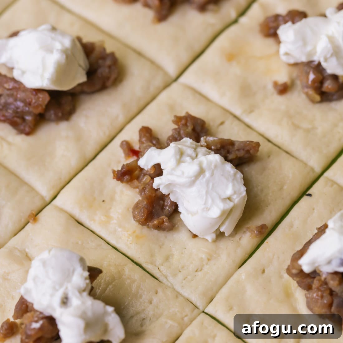 Spoonfuls of sausage and cream cheese on top of crescent rolls
