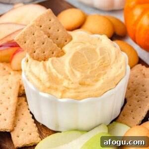 A white bowl filled with creamy pumpkin dip, topped with two graham crackers.