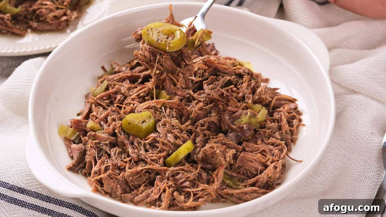 A white bowl filled with italian beef and sliced peppers.
