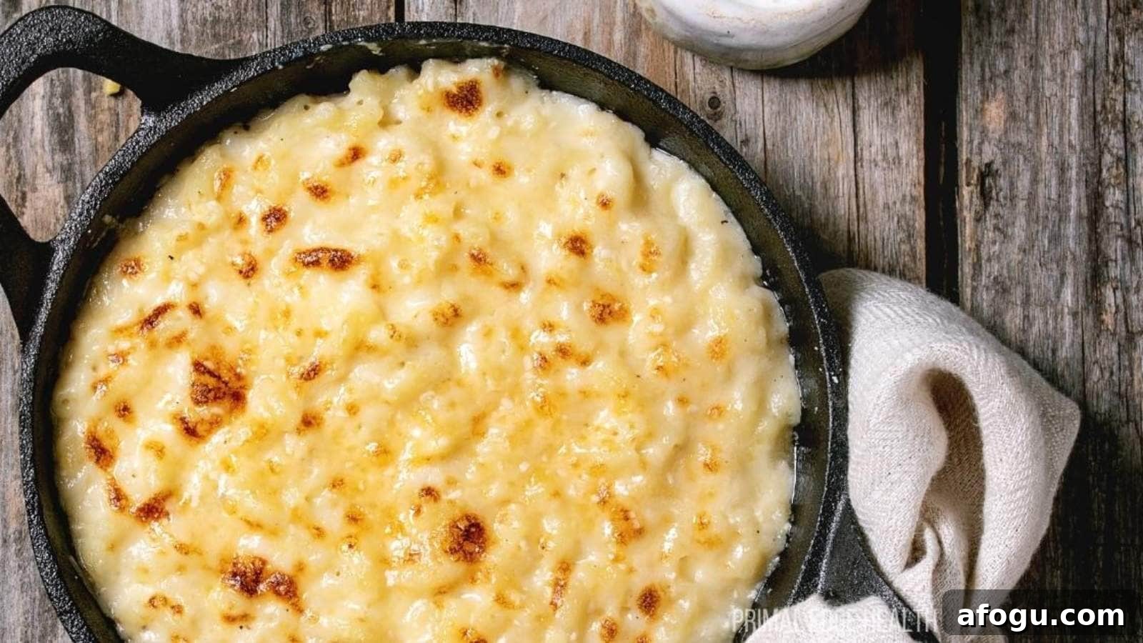 A picture of baked cauliflower mac and cheese in cast iron skillet on wooden table.