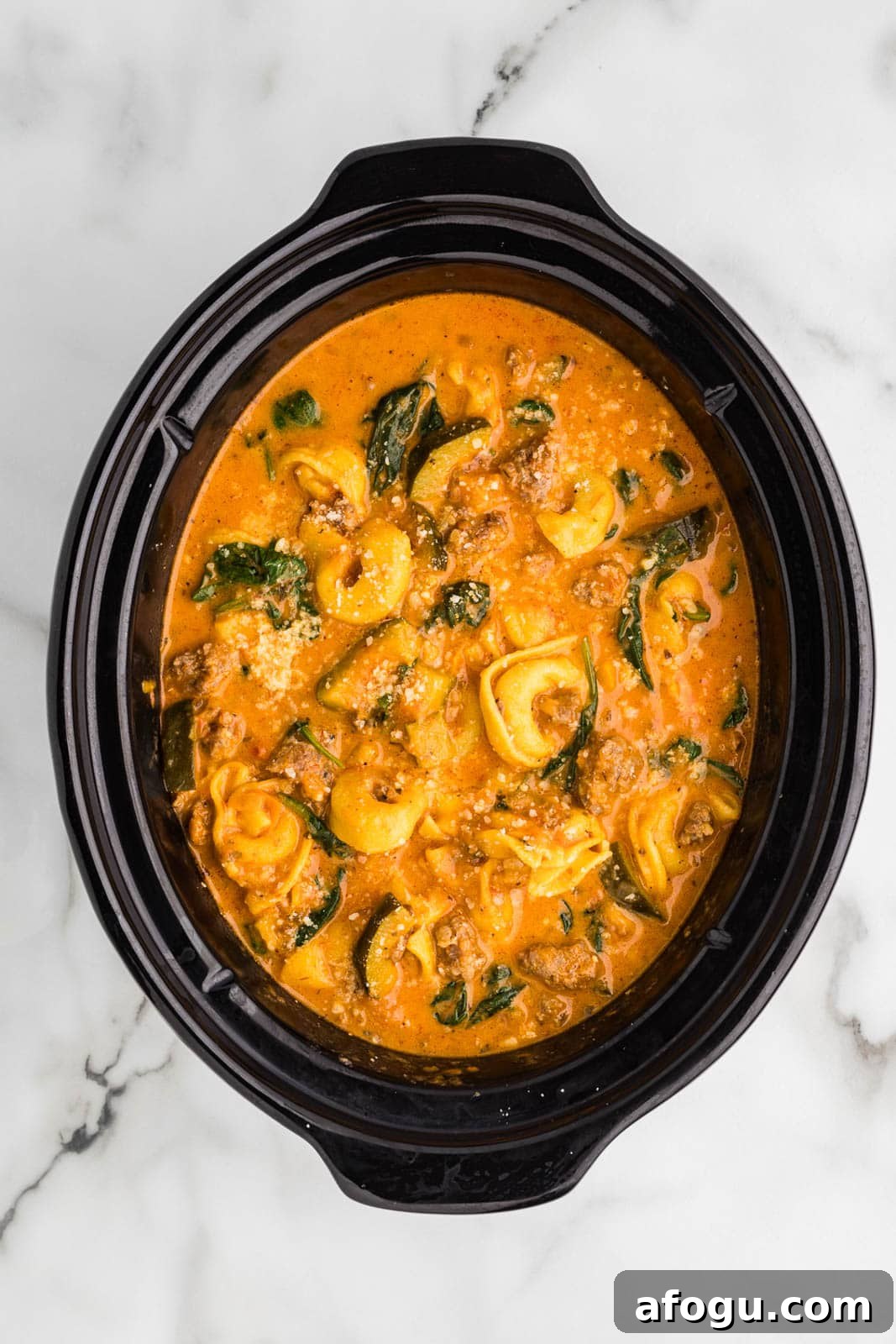 overhead view of black slow cooker with finished tortellini soup