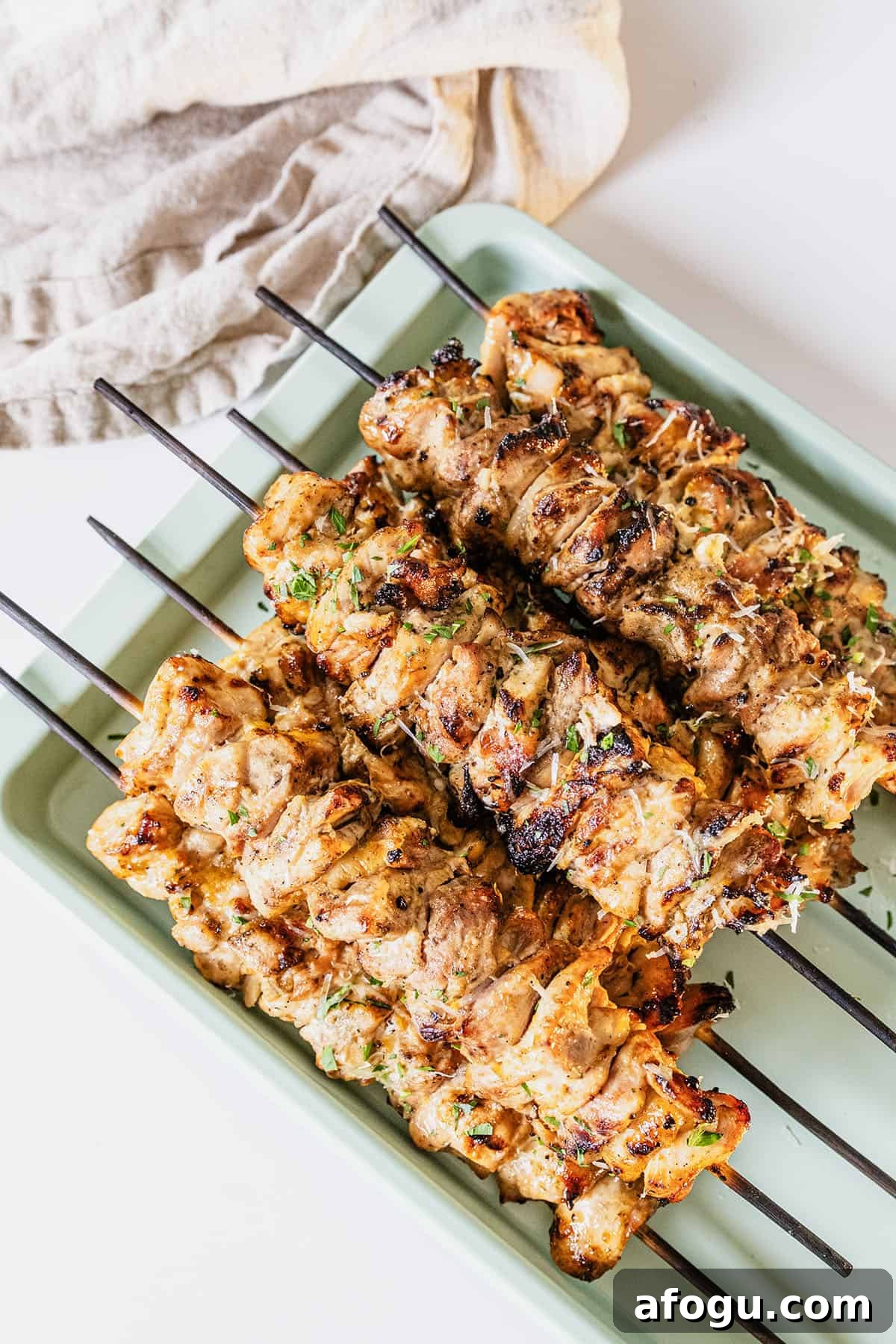 Garlic parm chicken skewers on a baking pan basted with parm sauce.
