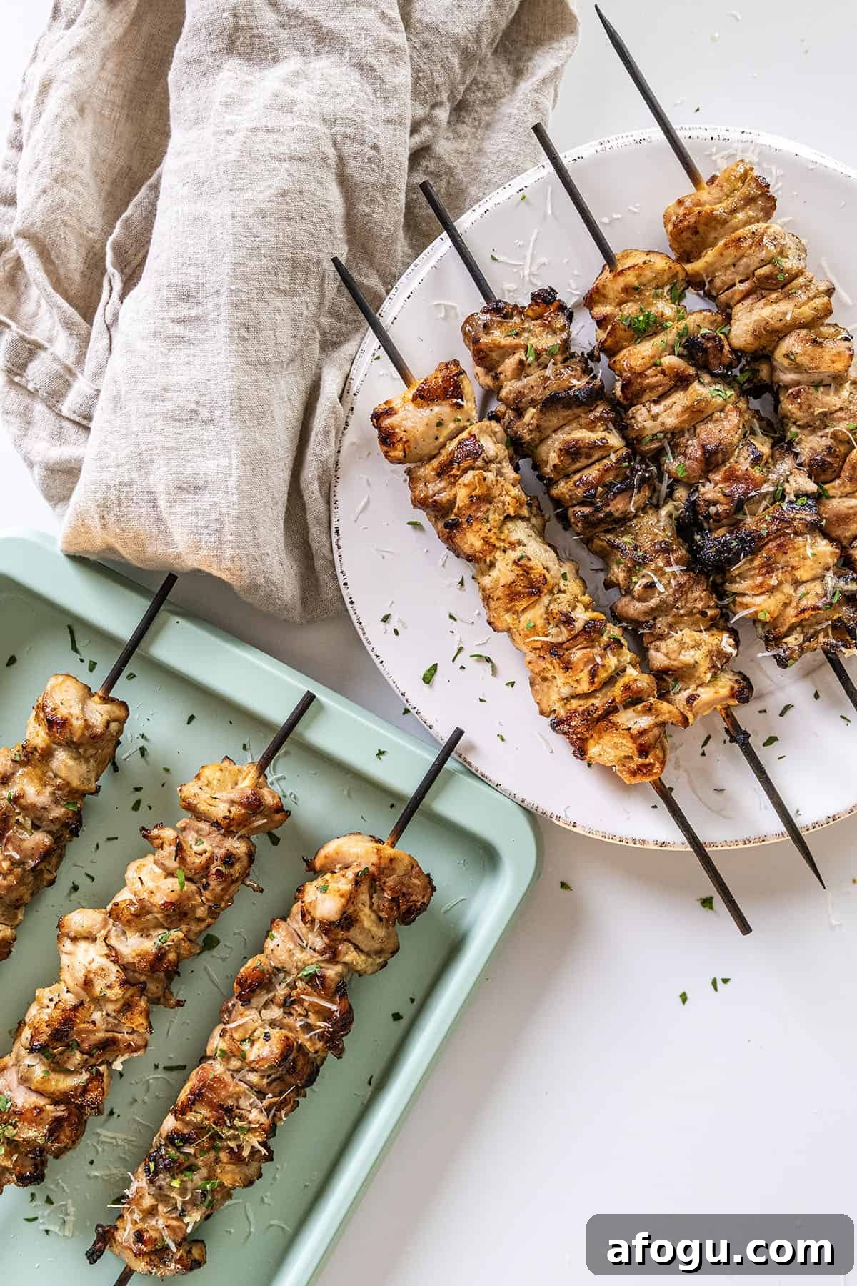 Garlic parm chicken skewers on a plate basted with parm sauce.