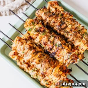 Garlic parm chicken skewers on a baking pan.