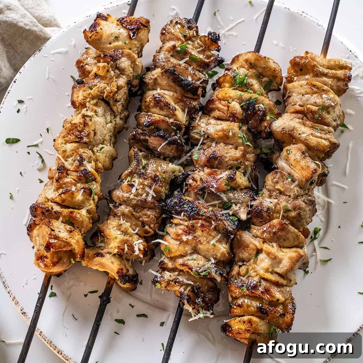 Garlic parm chicken skewers on a plate basted with parm sauce.