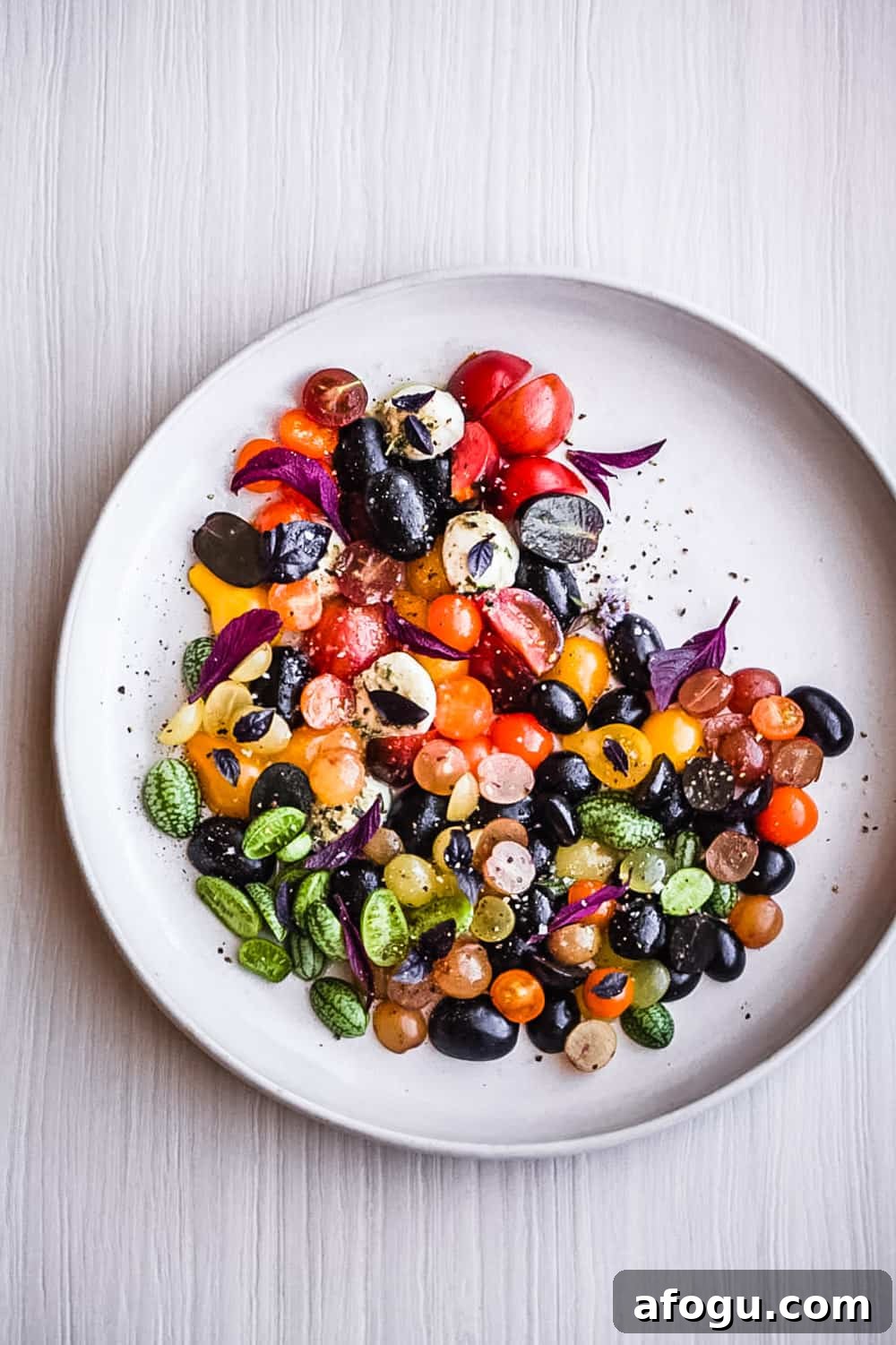Summer Salad Recipe That Keeps Giving All Season Long 11 a summer salad with cherry tomatoes, cucuamelons, grapes, basil and cheese arranged on a plate.