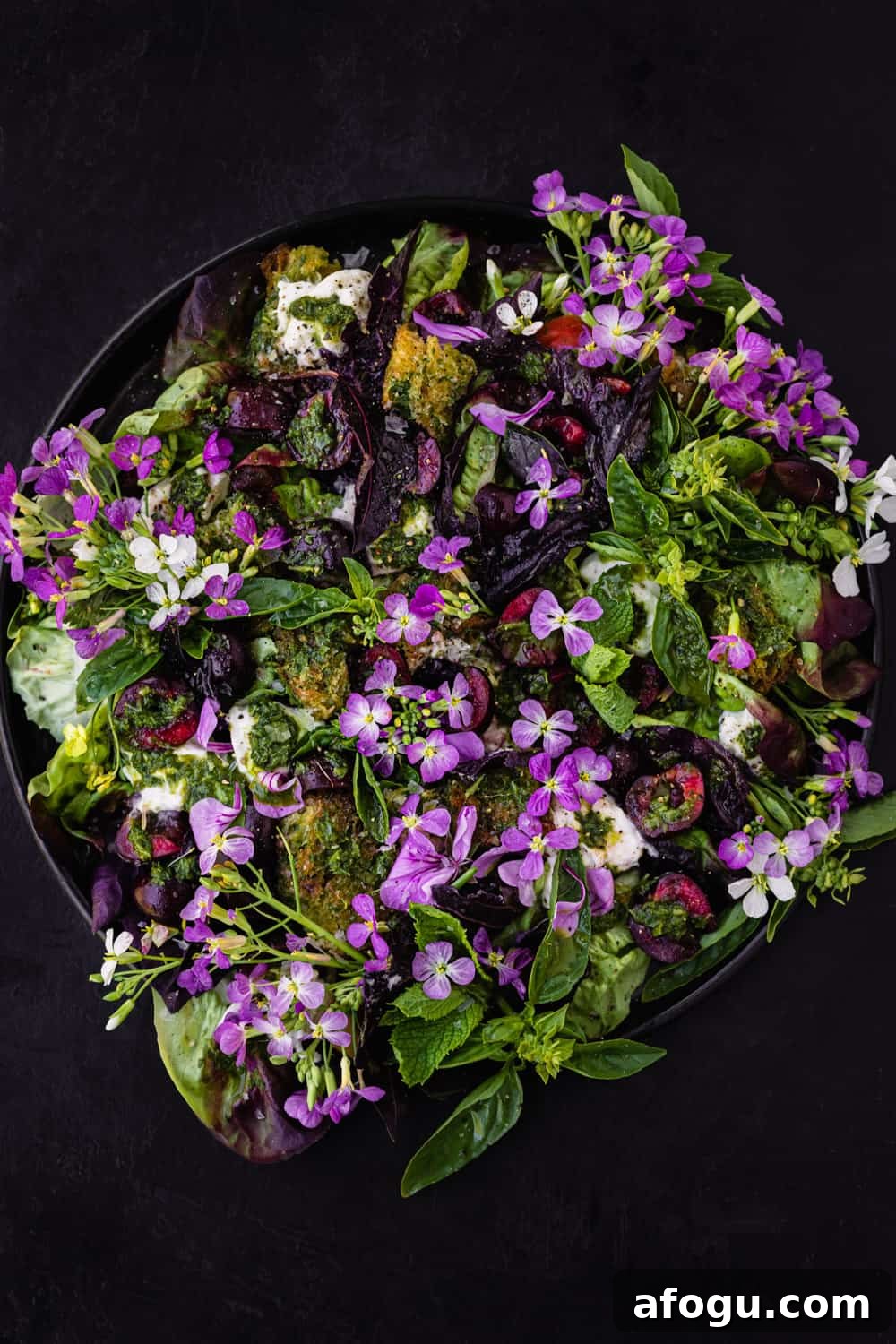 Summer Salad Recipe That Keeps Giving All Season Long 13 Summer cherry and fresh herb salad! with croutons, little gems, burrata and pesto vinaigrette on a black plate. Overhead shot on a black background.