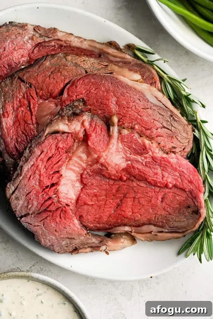 a platter of sliced prime rib roast garnished with rosemary