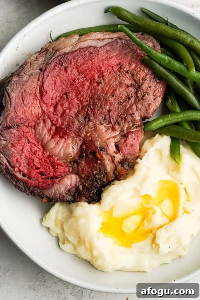 plated prime rib roast with a side of mashed potatoes and green beans