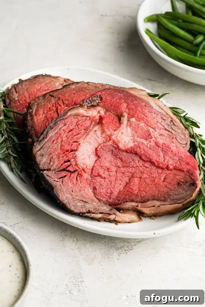 plated sliced prime rib roast with a plate of green beans in the background