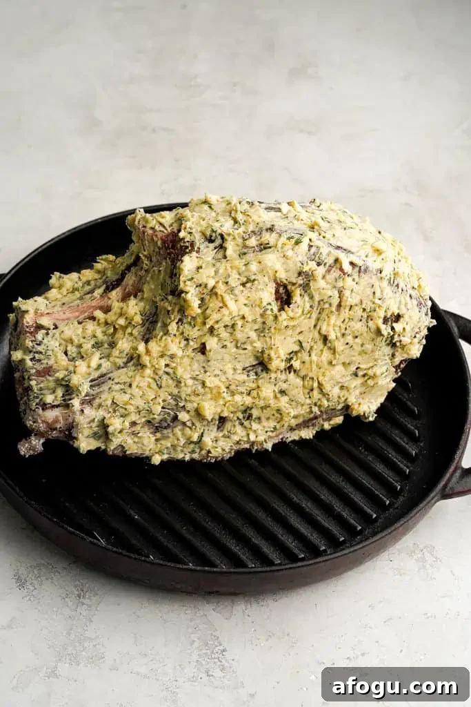 small prime rib roast coated with butter in a skillet with a wire rack beneath it