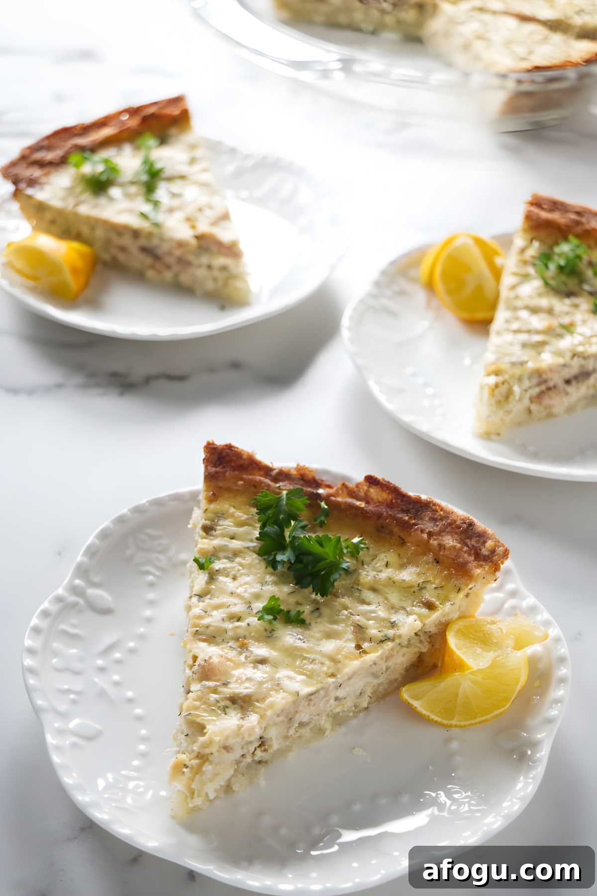 Salmon and Potato Crust Quiche – Savory Brunch Recipe 3 Three salmon potato quiche slices on white plates with parsley and lemon garnish.