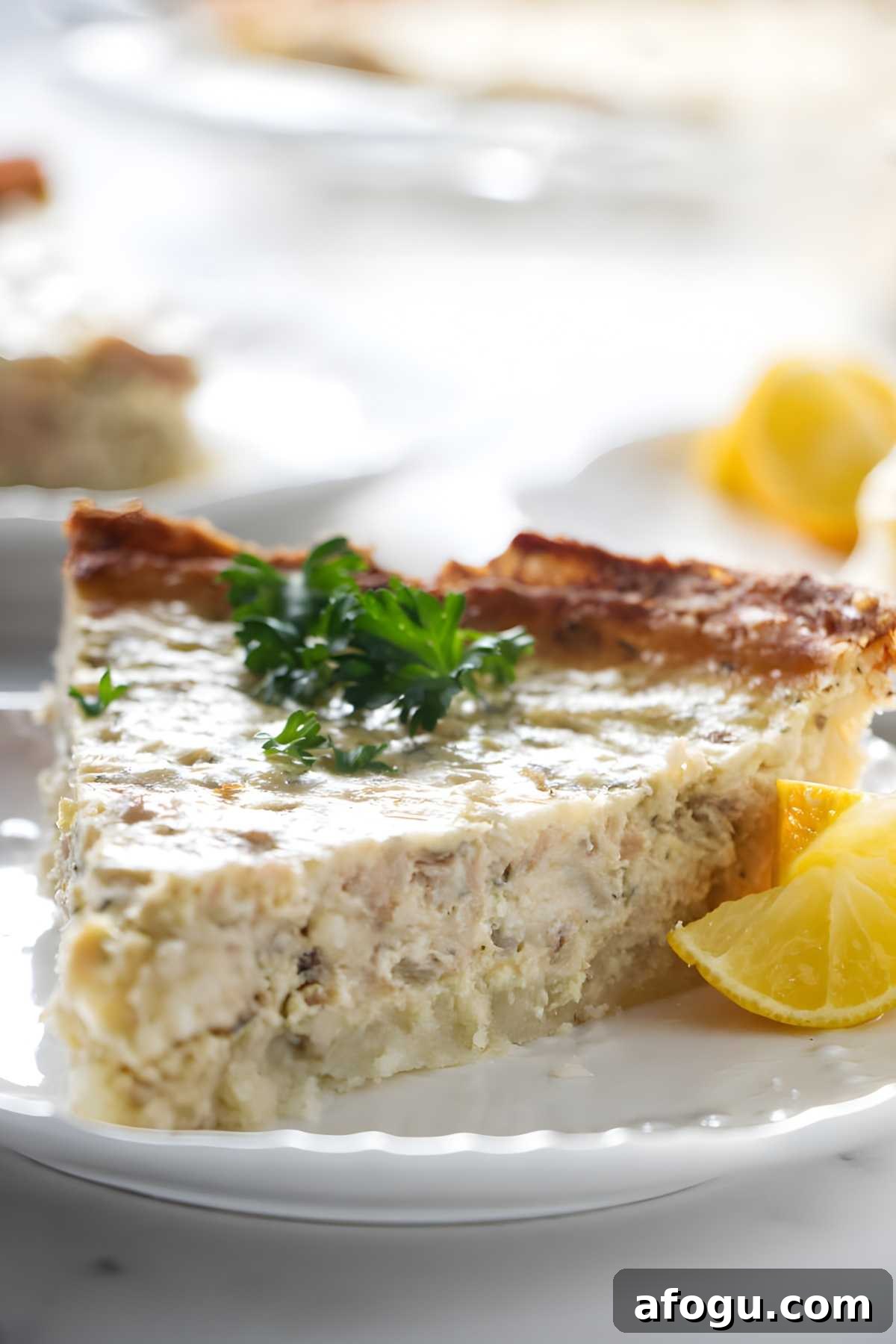 Salmon and Potato Crust Quiche – Savory Brunch Recipe 4 Close-up of savory quiche slice with parsley and lemon wedges on a plate.