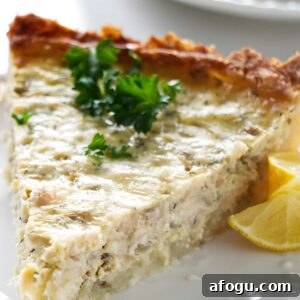 Salmon and Potato Crust Quiche – Savory Brunch Recipe 5 Close-up of a quiche slice with parsley and lemon wedges on a plate.