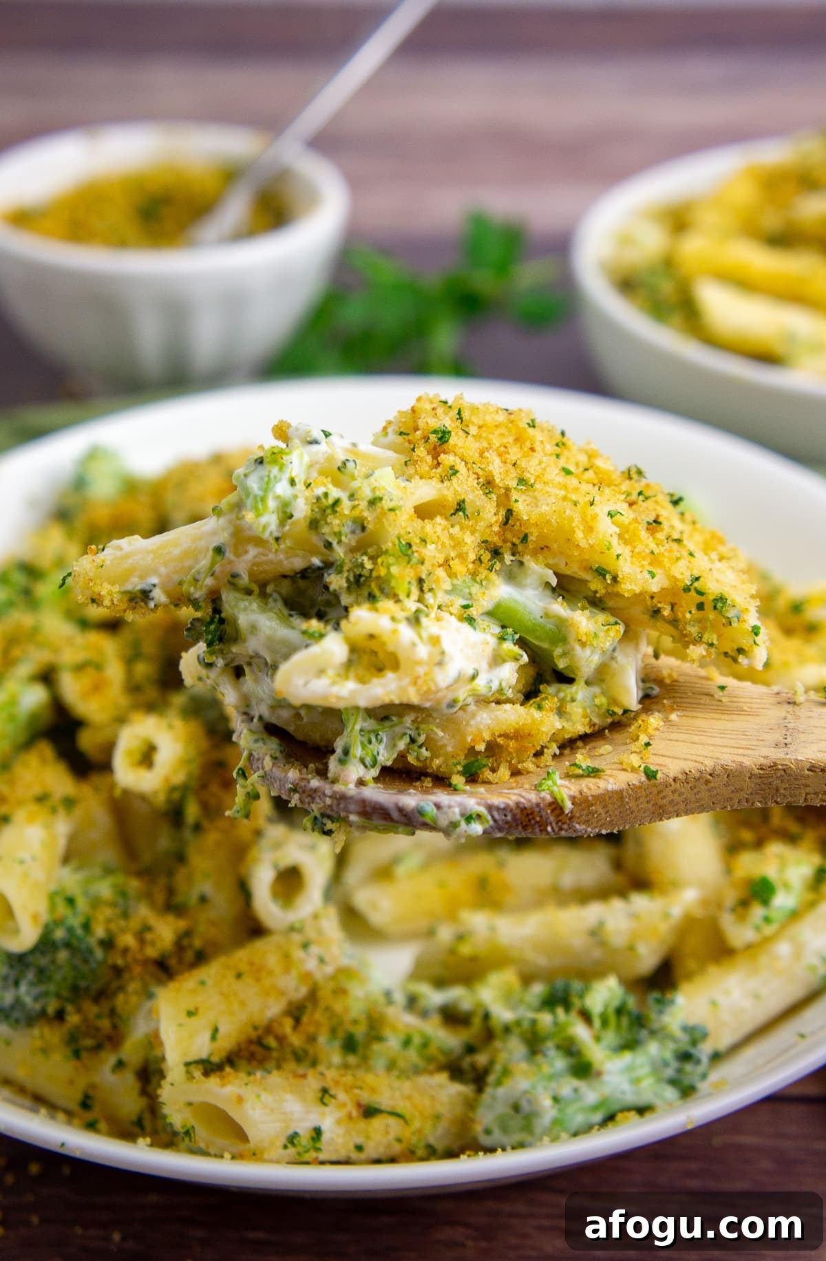 a large white bowl of penne pasta with broccoli topped with breadcrumbs.