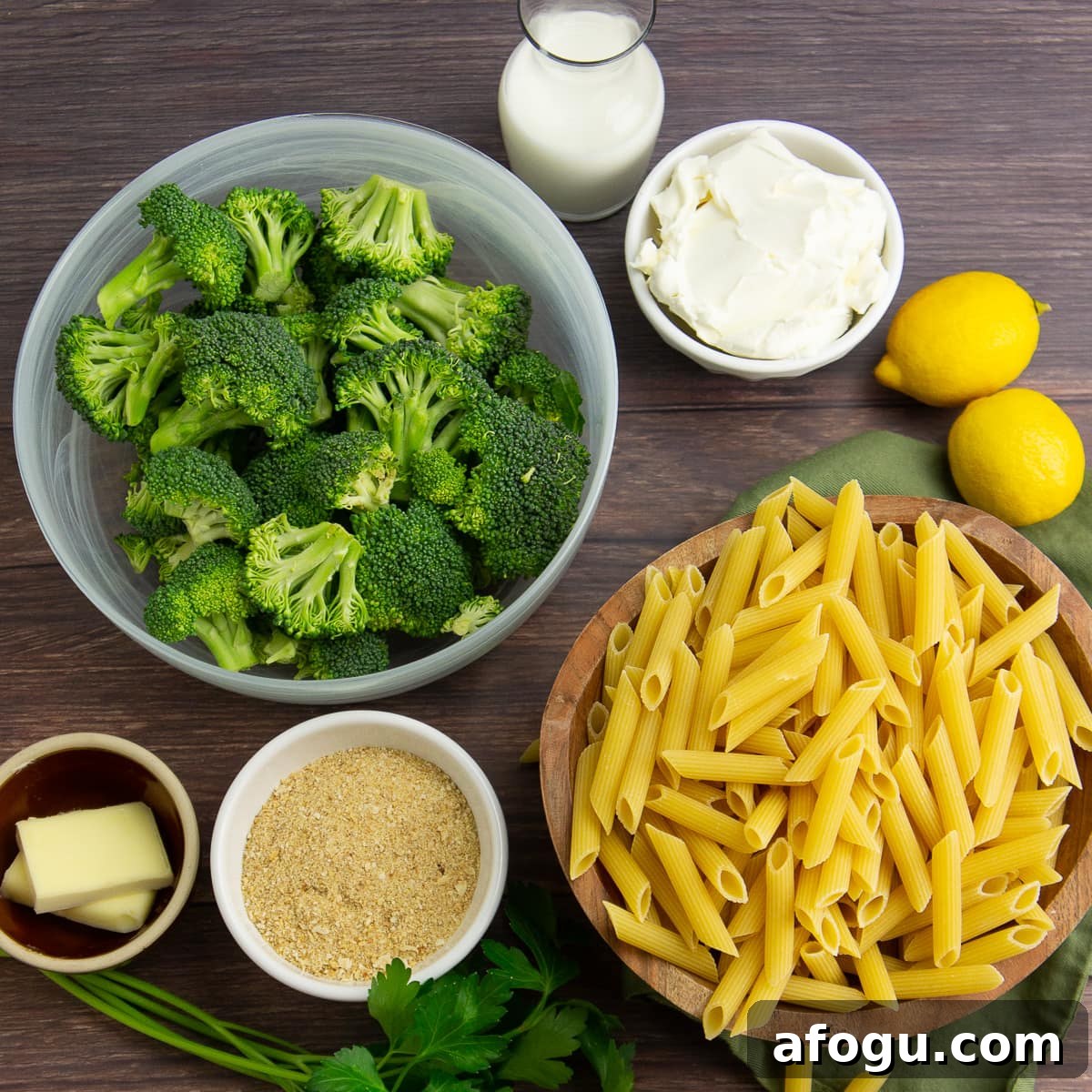 Ingredients to make broccoli pasta like dried penne, breadcrumbs, cream cheese, lemons, butter, and broccoli.