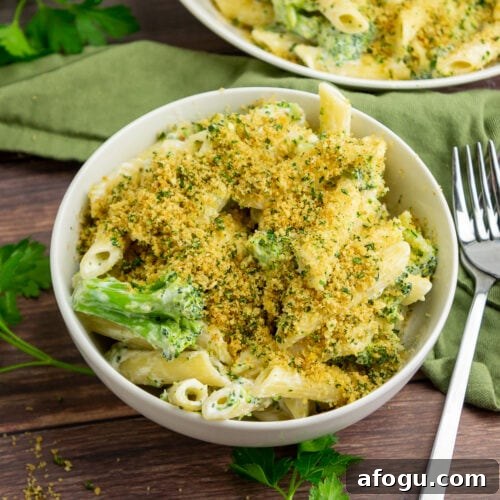 a white bowl of pasta with broccoli and breadcrumbs.