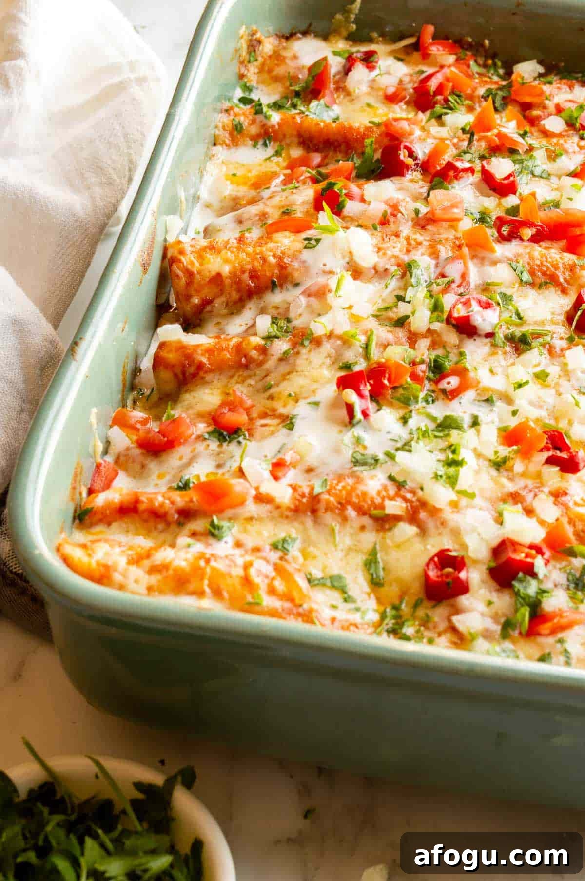 Front view of a green casserole dish with cheese-topped enchiladas.
