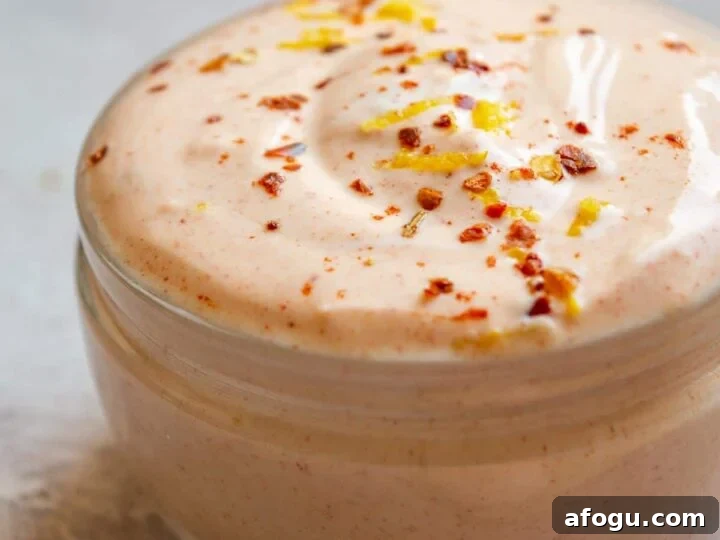 A jar of thick cream with chili flakes and lemon zest on top.