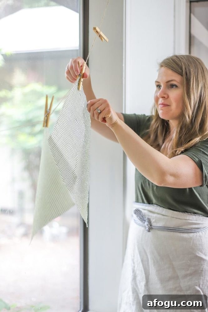 DIY Beeswax Food Wraps: Step-by-Step Guide for Reusable Wraps 3 women wearing a green dress and an apron is hanging beeswax wraps on a clothes like with clothes pins