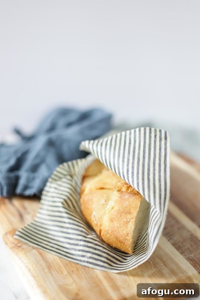 DIY Beeswax Food Wraps: Step-by-Step Guide for Reusable Wraps 4 half a loaf of bread wrapped with beeswax wrap on a cutting board with a blue towel in the background