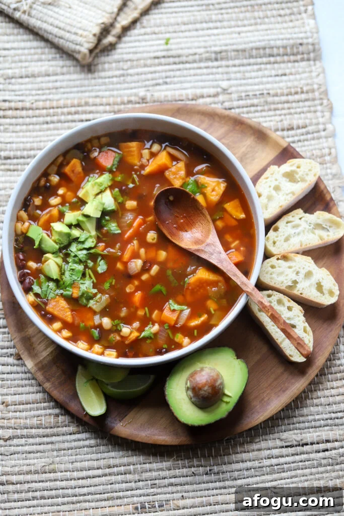 overhead view of a bowl containing vegan black bean and sweet potato soup next to avocado and toast.