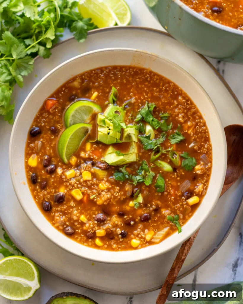overhead view of a white bowl with vegan Black Bean and Quinoa Soup with cilantro and fresh lime.