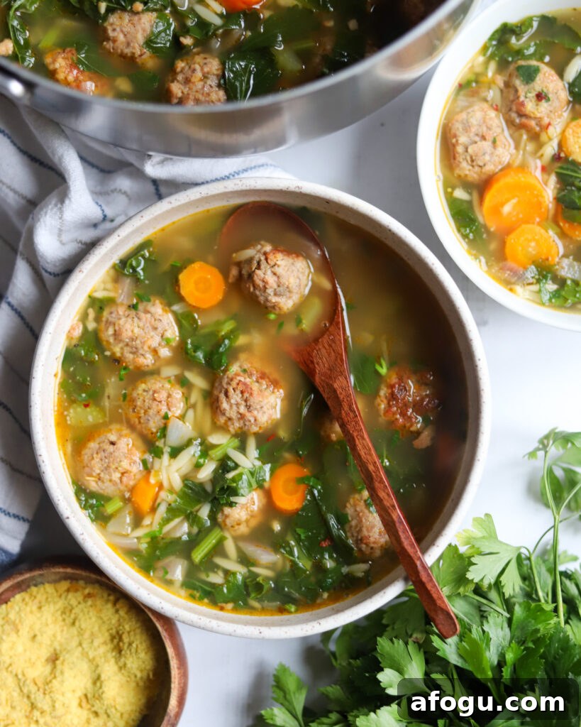 overhead view of vegan Italian Wedding Soup with meatballs, greens, herbs and carrots