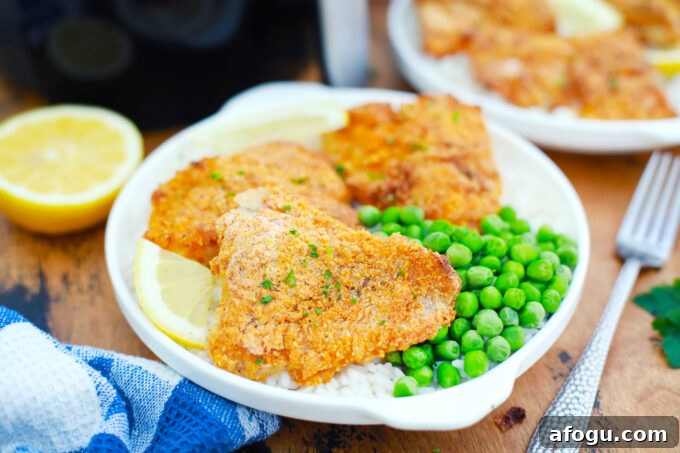 Air fryer crispy fish fillets served with rice and green peas.