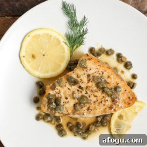 Plated swordfish piccata with golden seared edges, topped with a lemon butter caper sauce and fresh herbs, served as a light, elegant dinner.