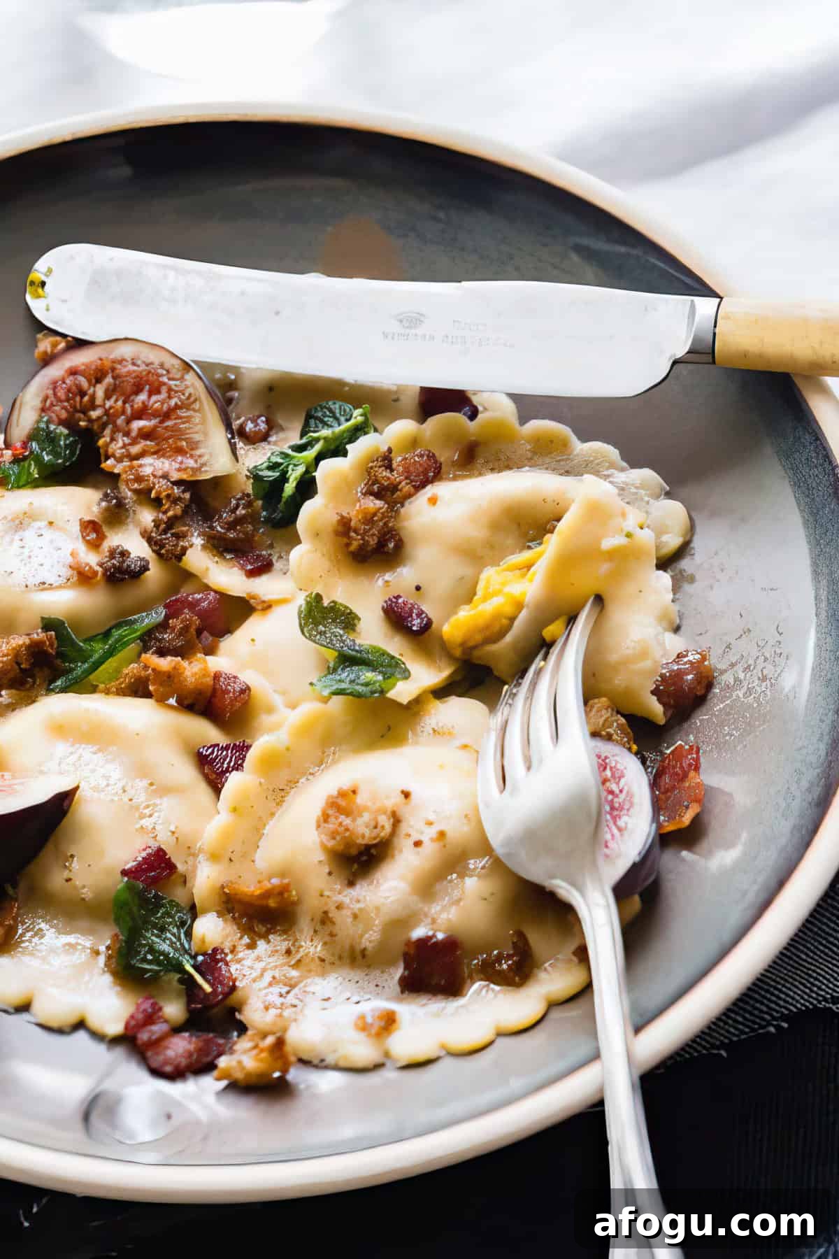 Pumpkin ravioli with sage and brown butter on a white table.