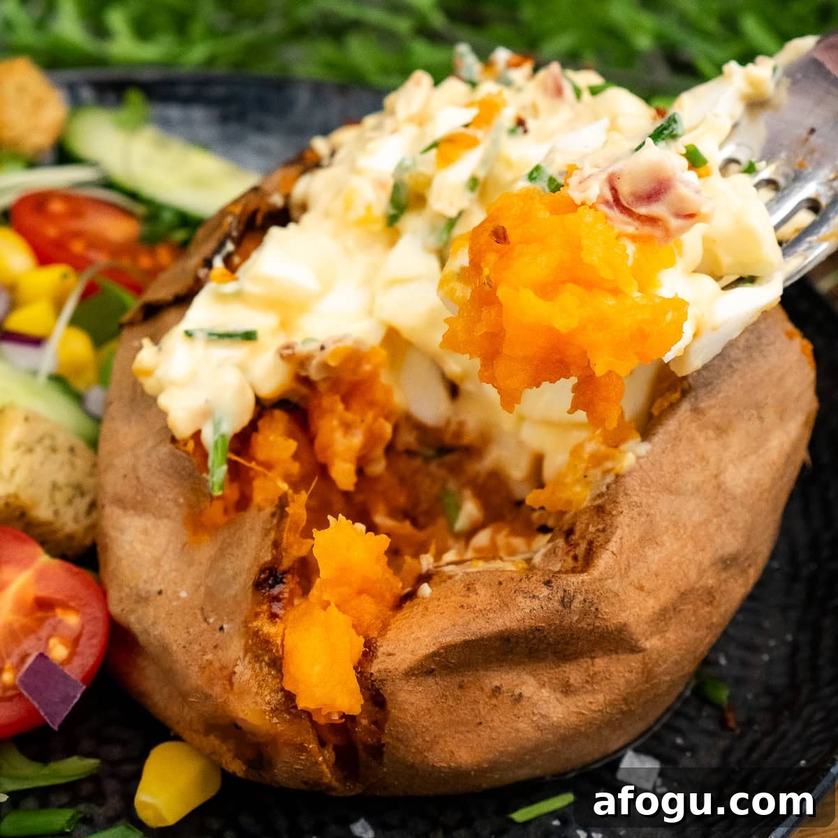 Jacket Sweet Potato in the Air Fryer being picked up with a fork with egg mayo filling and chopped chives