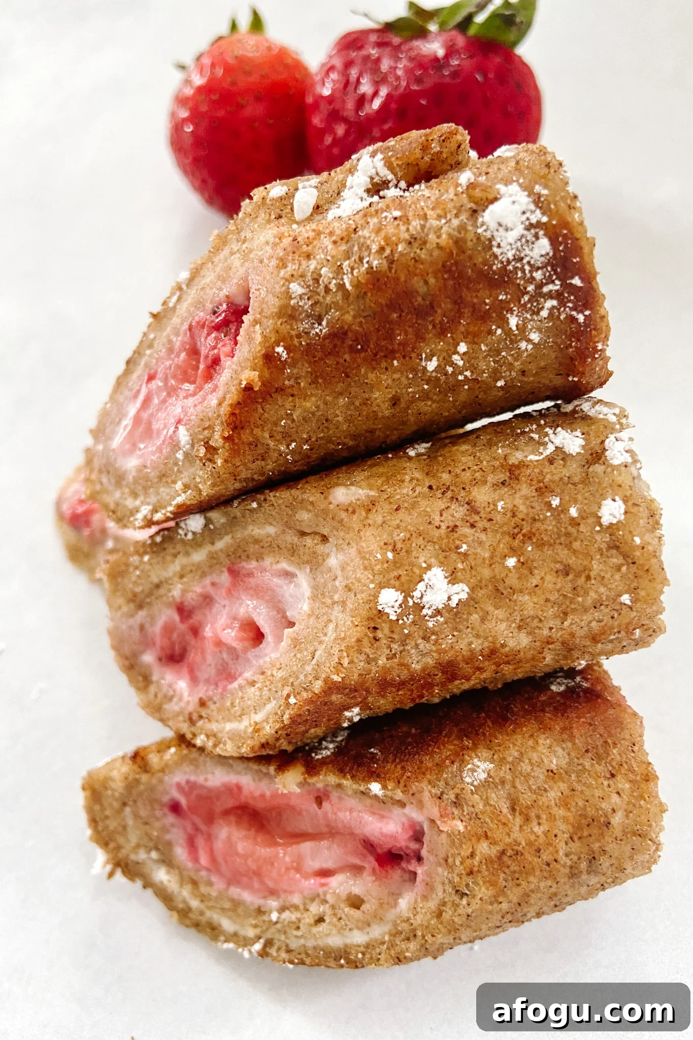 Strawberry cheesecake rollups served with strawberries and lightly dusted with powdered sugar
