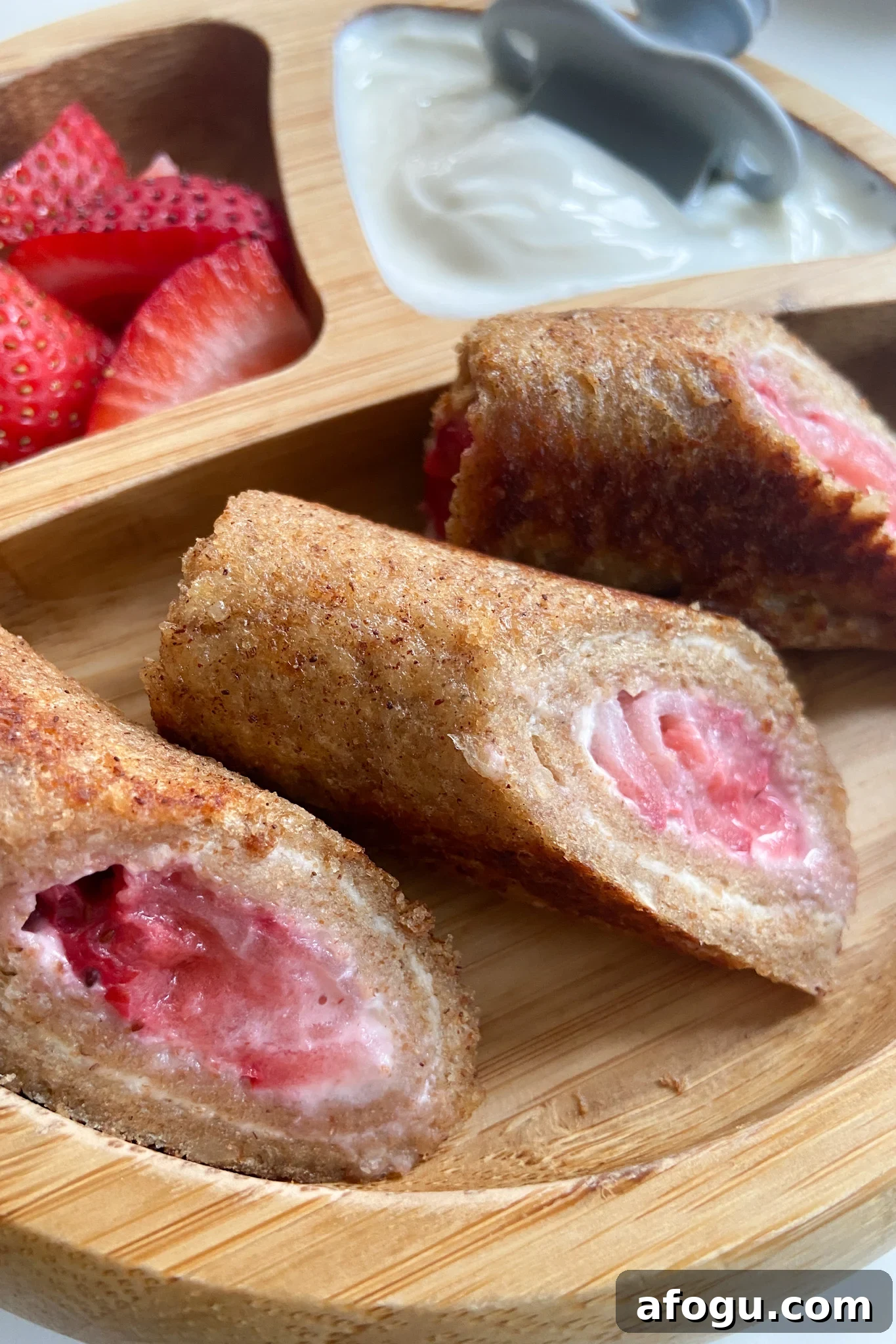Strawberry cheesecake rollups served with sliced strawberries and yogurt