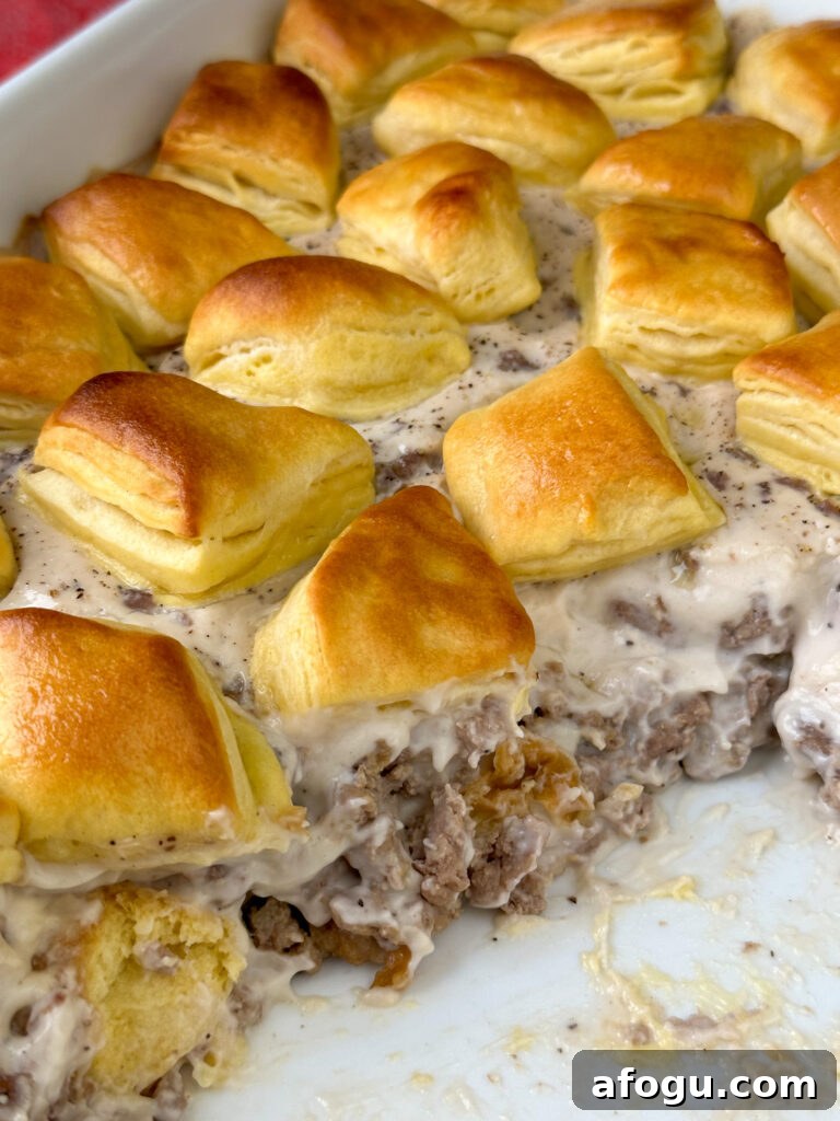 Close up showing a generous layer of sausage gravy between two layers of biscuits.