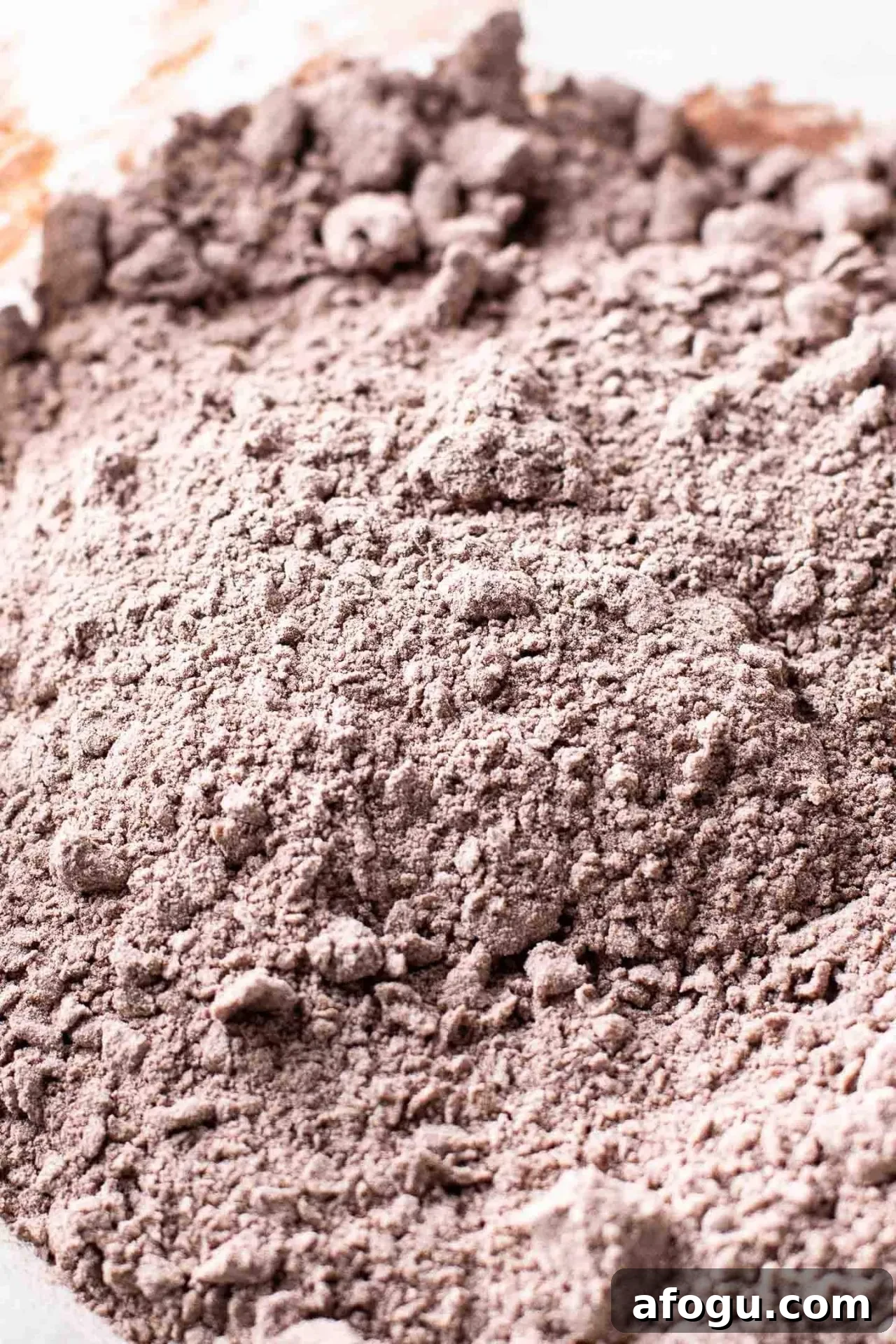 chocolate sour cream frosting powdered sugar, cocoa powder, and butter combined into a crumbly mixture in bowl