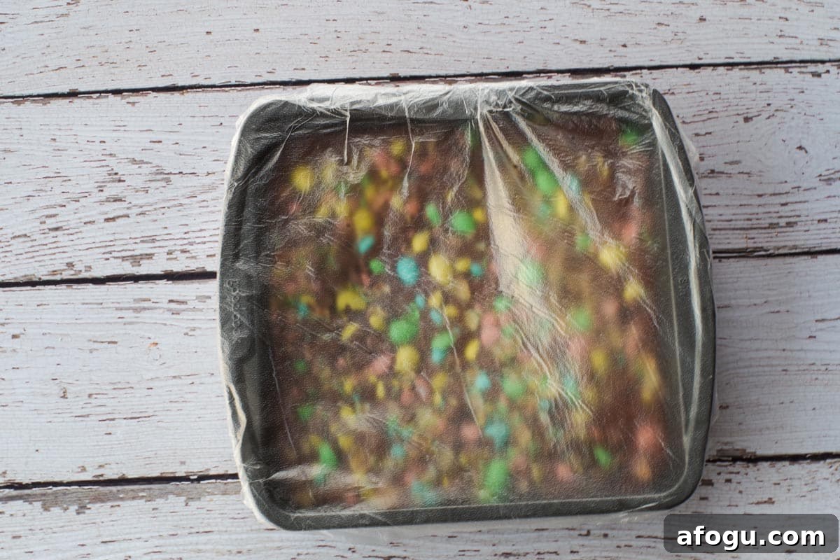 Mini egg fudge ready to go into fridge, covered in plastic wrap.