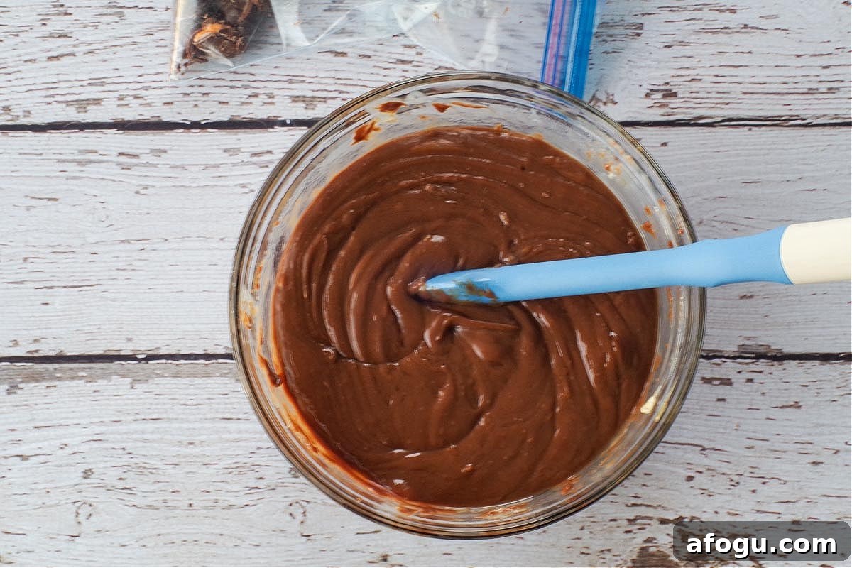 Microwaved chocolate mixture in a glass bowl with a spatula.