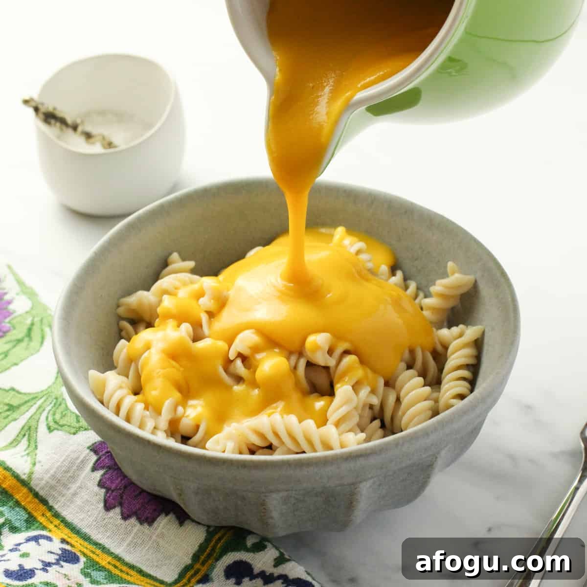 a pale blue bowl of pasta with healthy vegan cheese sauce