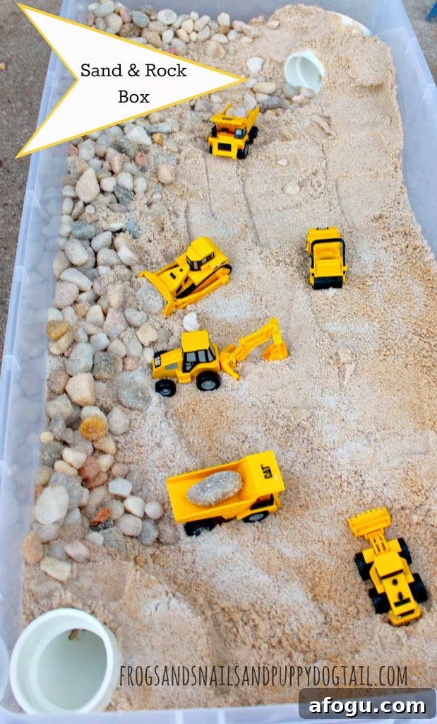 a plastic box with sand, rocks, and toy trucks