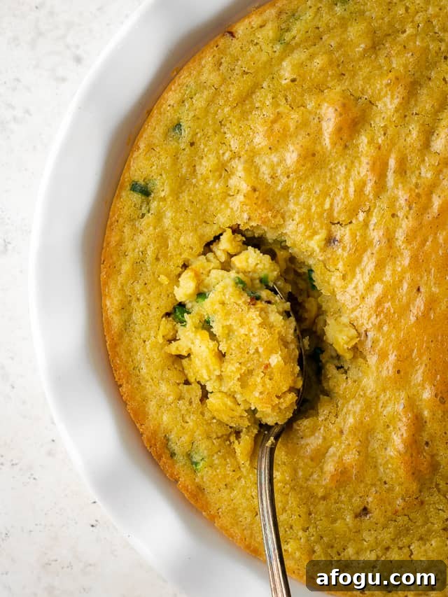 A spoon scooping up a serving of gluten free corn casserole from a casserole dish.