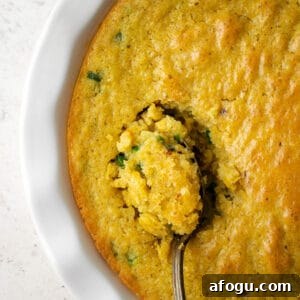 A spoon of gluten free corn casserole being served from a dish.