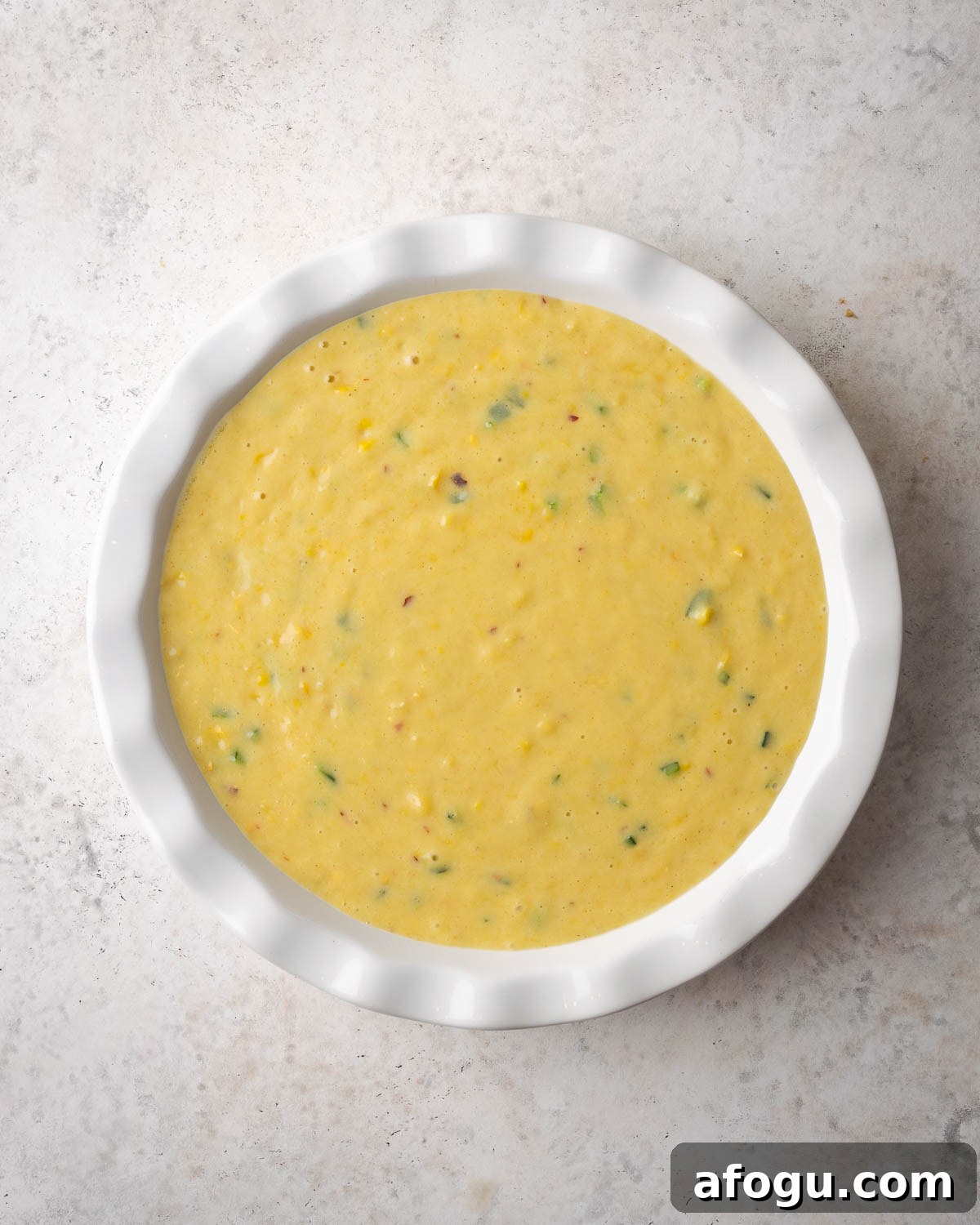 Unbaked corn casserole in a white baking dish.